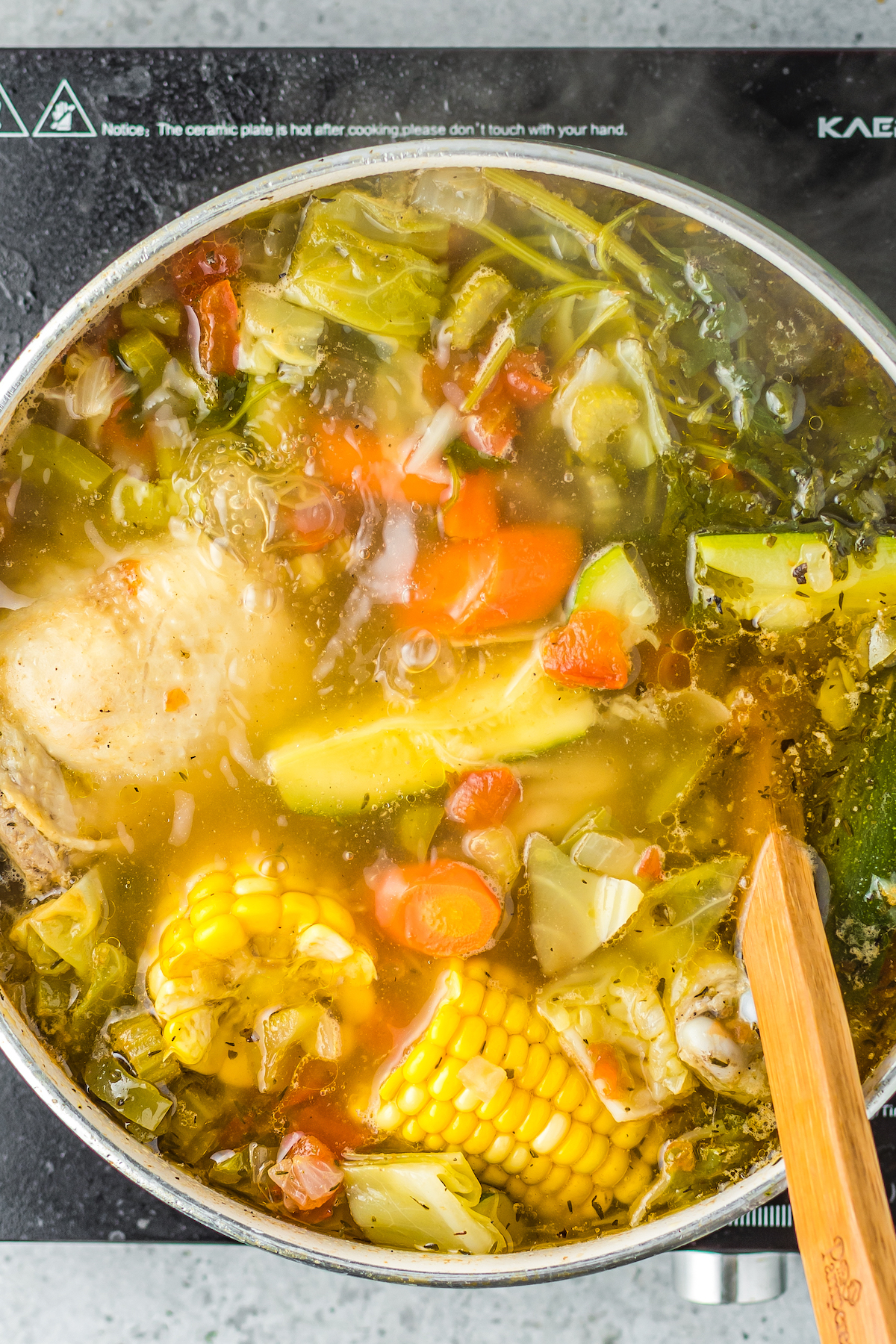 chicken, corn, potatoes, and fresh herbs simmering in a stockpot