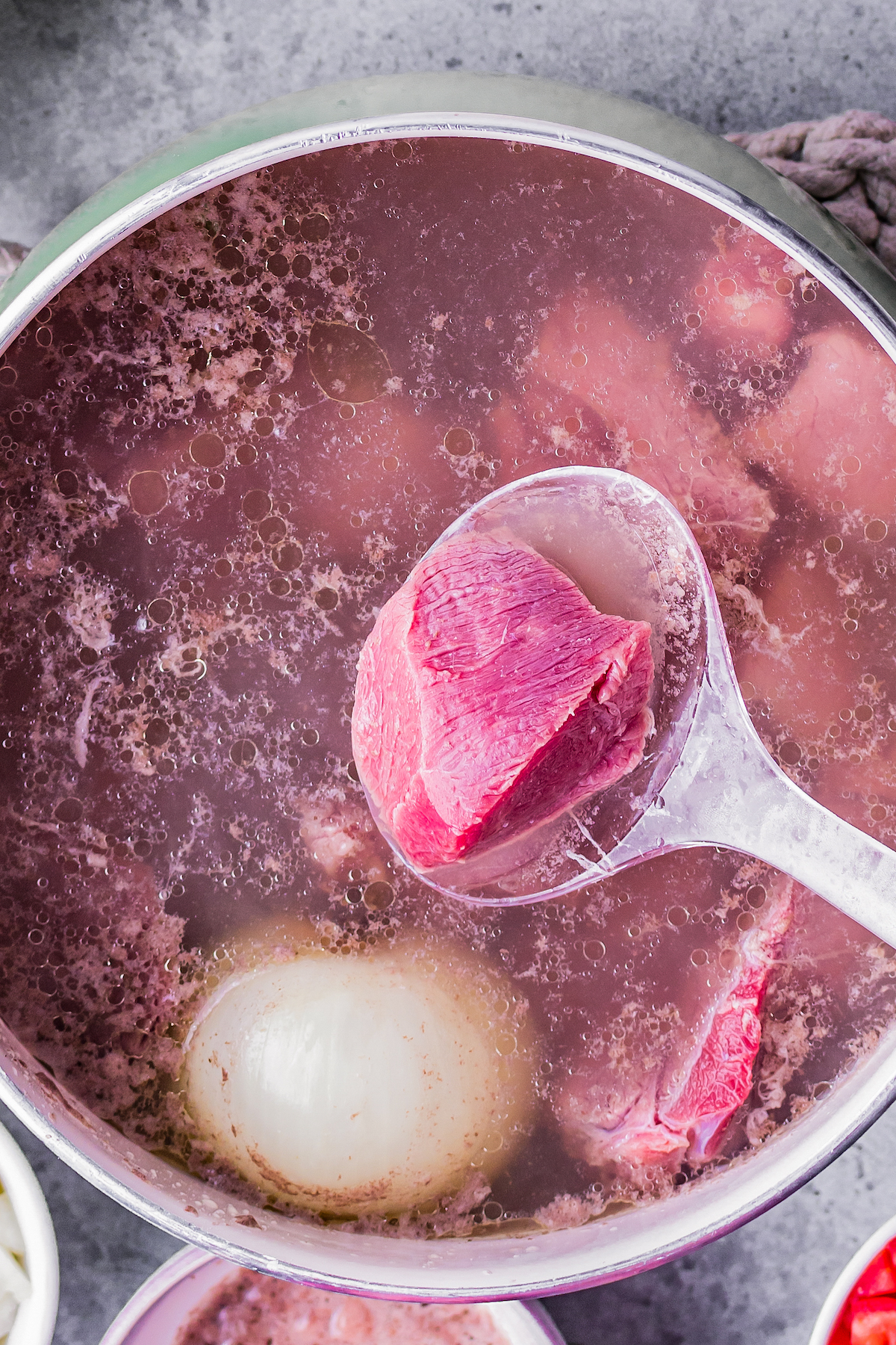 beef simmering in broth with an onion in a pot