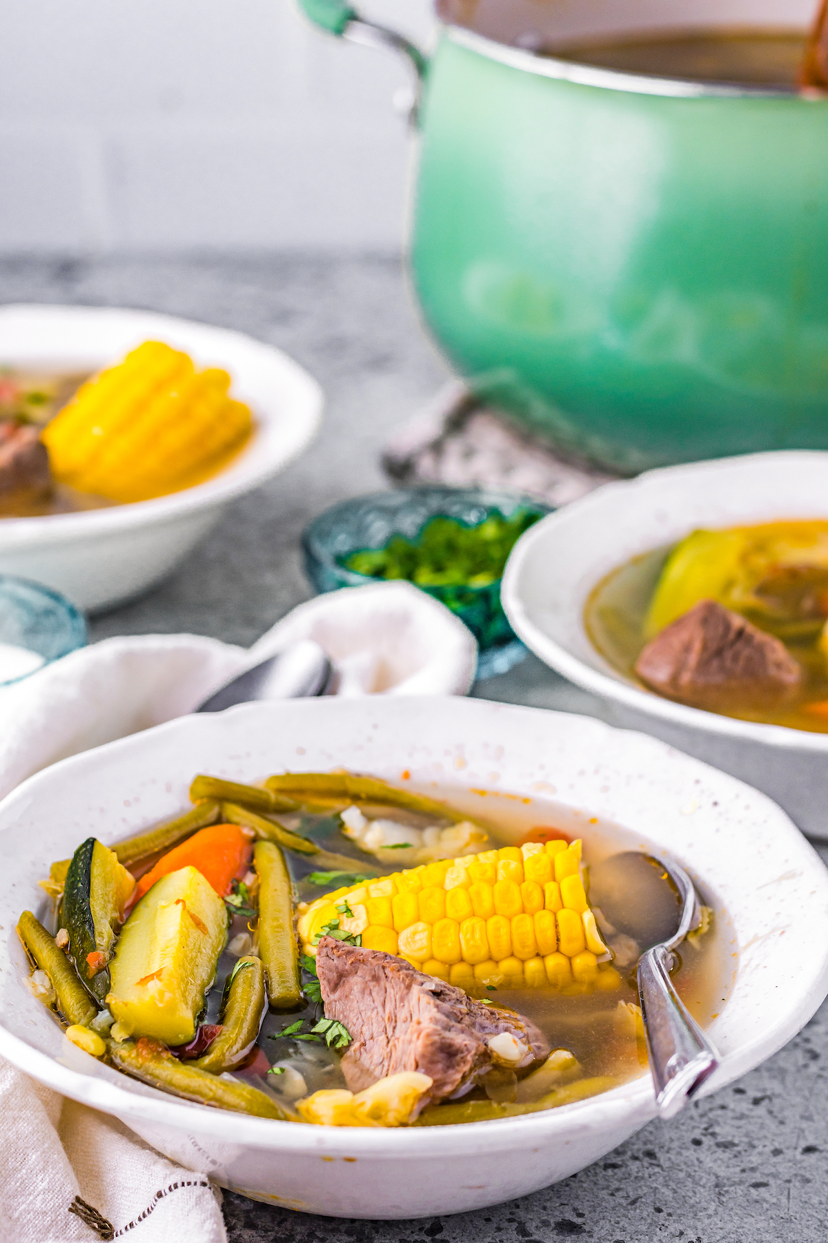 Mexican beef stew with zucchini, corn, fresh herbs, green beans, in a beef-based broth served in a bowl 