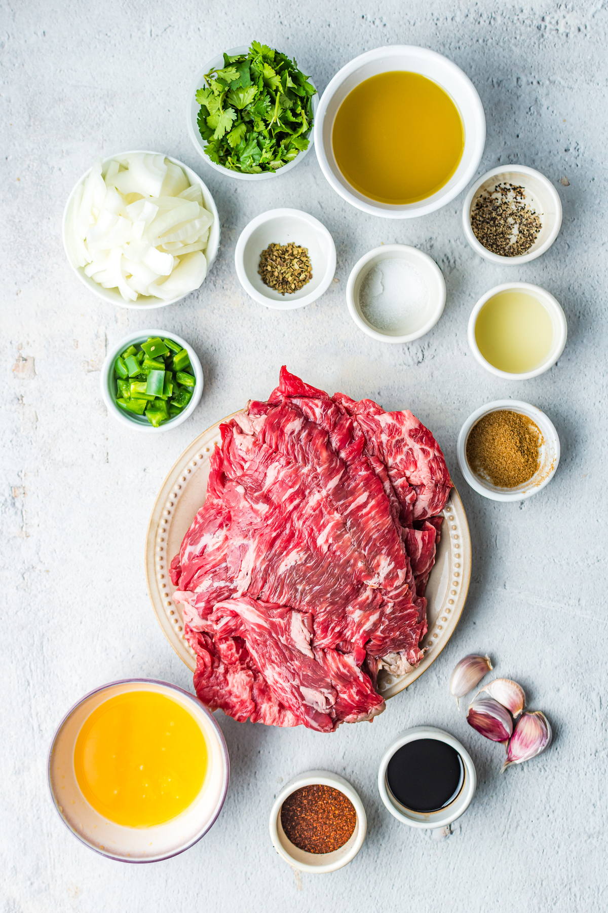 From top: Chopped cilantro, olive oil, chopped onion, salt and pepper, white vinegar, seasonings, lime juice, finely chopped jalapeno, flank steak, cumin, pineapple juice, chili powder, maggi jugo, garlic.