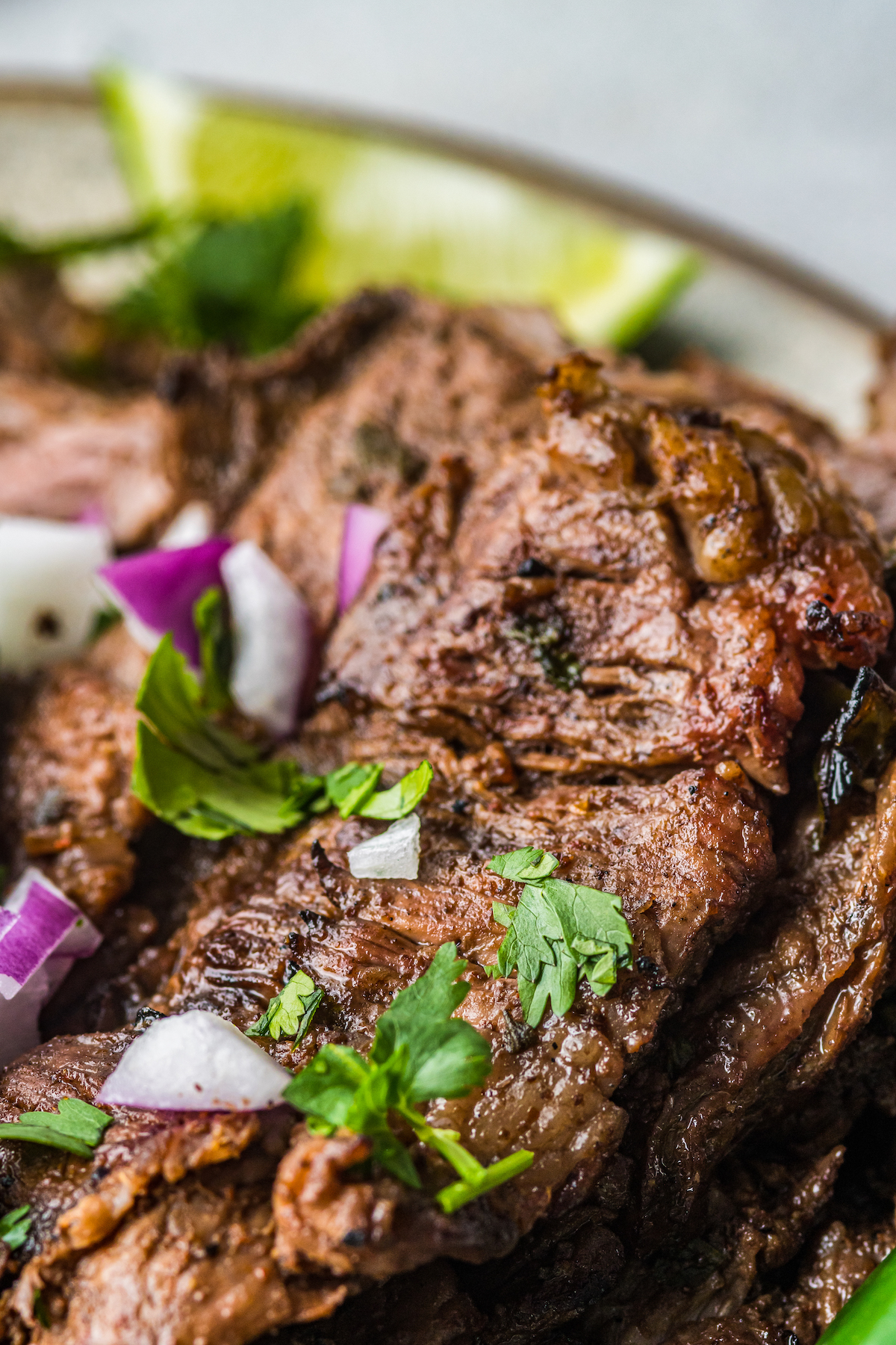 Grilled steak, garnished with chopped red onion and cilantro.