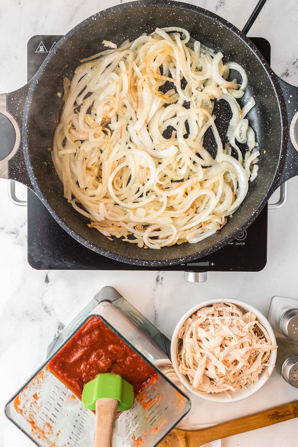 onions caramelizing in a pan next to a bowl of shedded chicken and red sauce