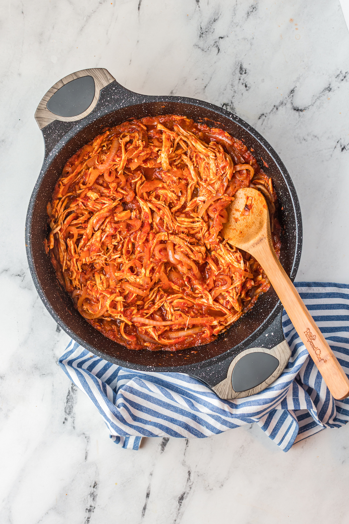 Shredded chicken in a red sauce in a skillet