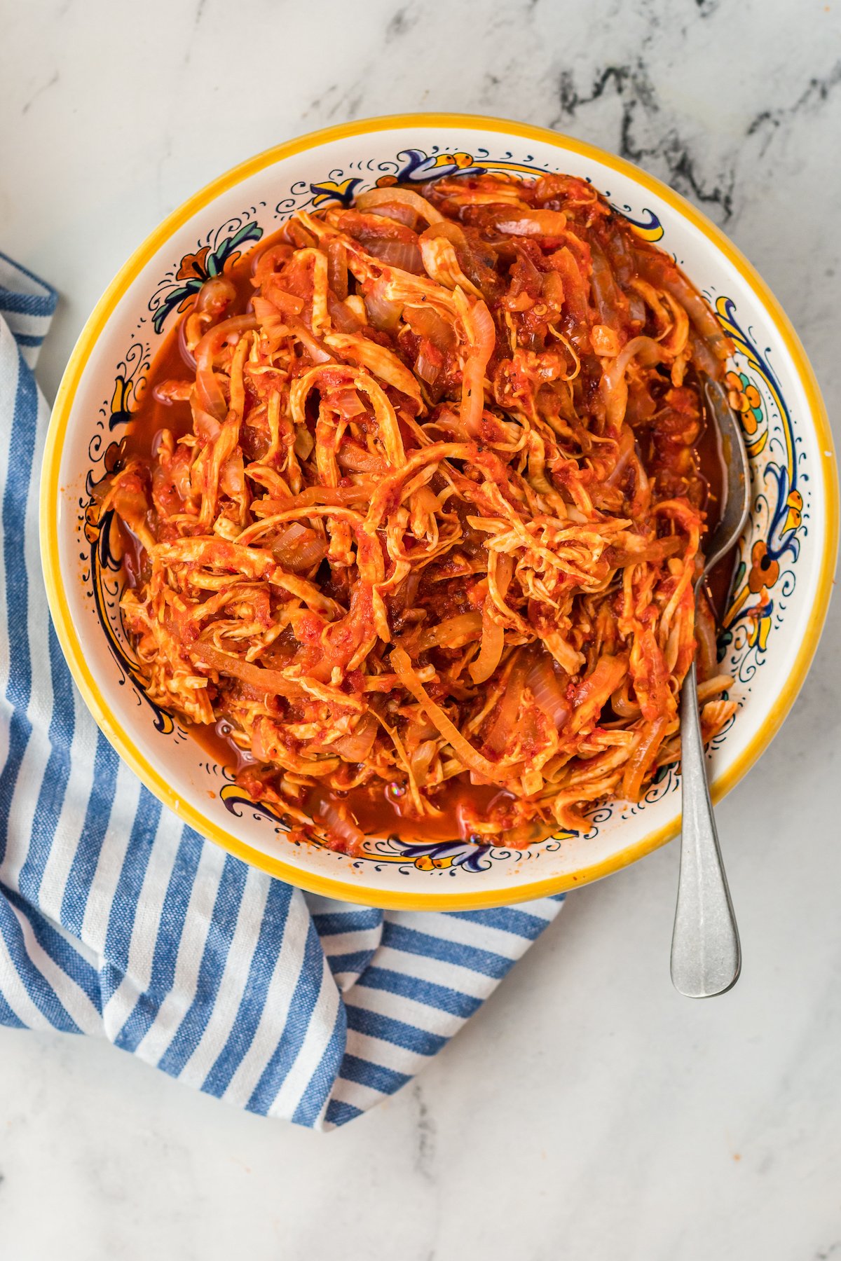 Shredded chicken in a red sauce in a bowl