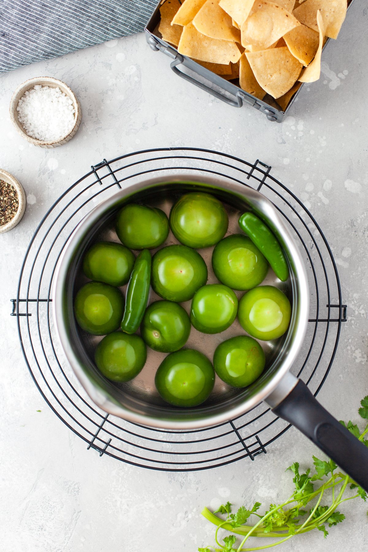 tomatillos and peppers in a pan with water