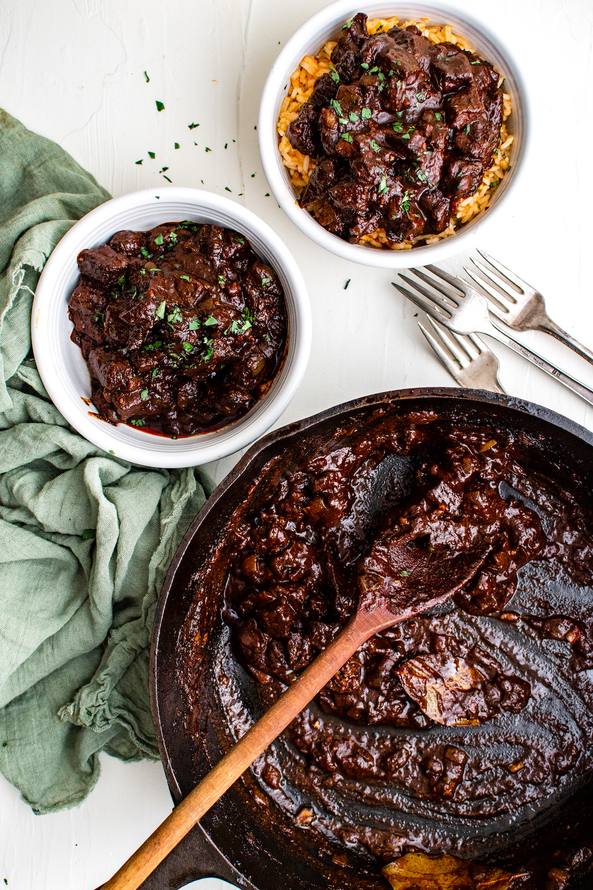 Mexican beef stew in a red chili-based sauce served in bowls with forks on the side.