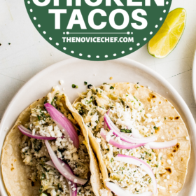 Two tacos filled with salsa verde chicken, onions, cheese and lime wedges.