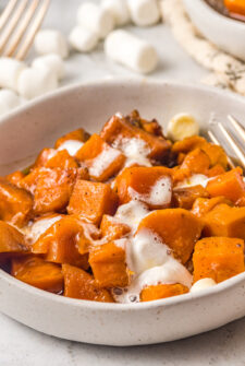 cubed sweet potatoes with melted mini marshmallows on top in a small white serving bowl