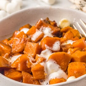 cubed sweet potatoes with melted mini marshmallows on top in a small white serving bowl