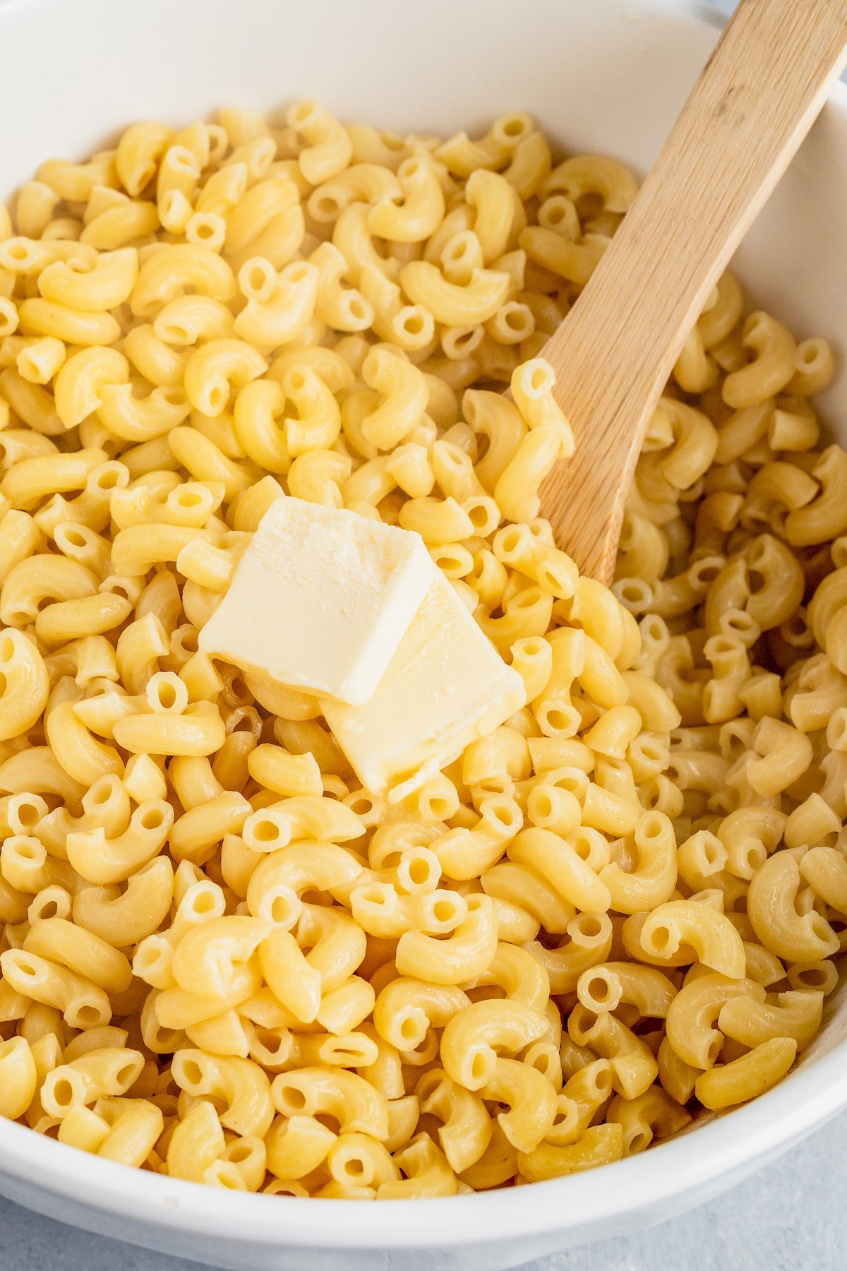 Butter being stirred into hot pasta.