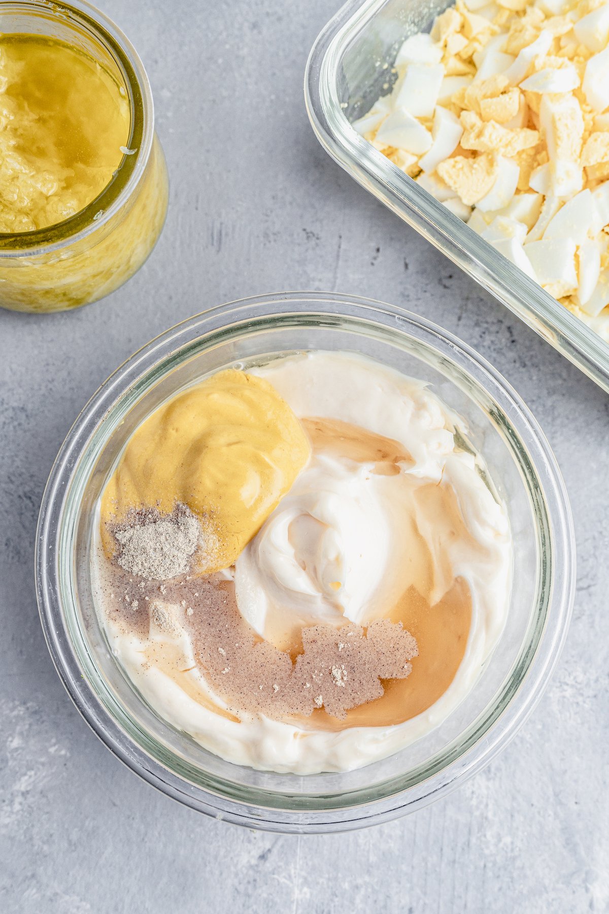 Mayonnaise, mustard, salt, pepper, and other dressing ingredients in a glass bowl.