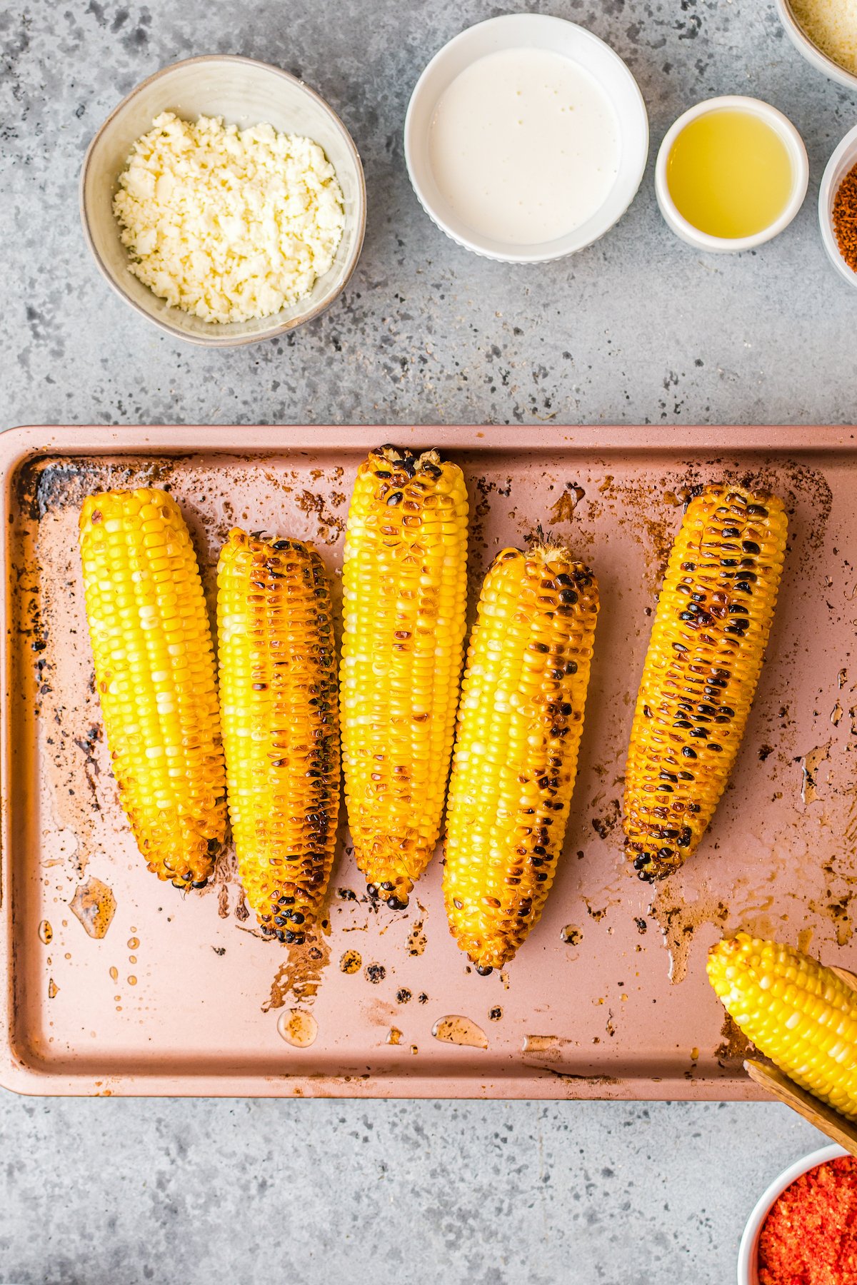 Broiled corn, lightly charred in places, on a baking sheet.