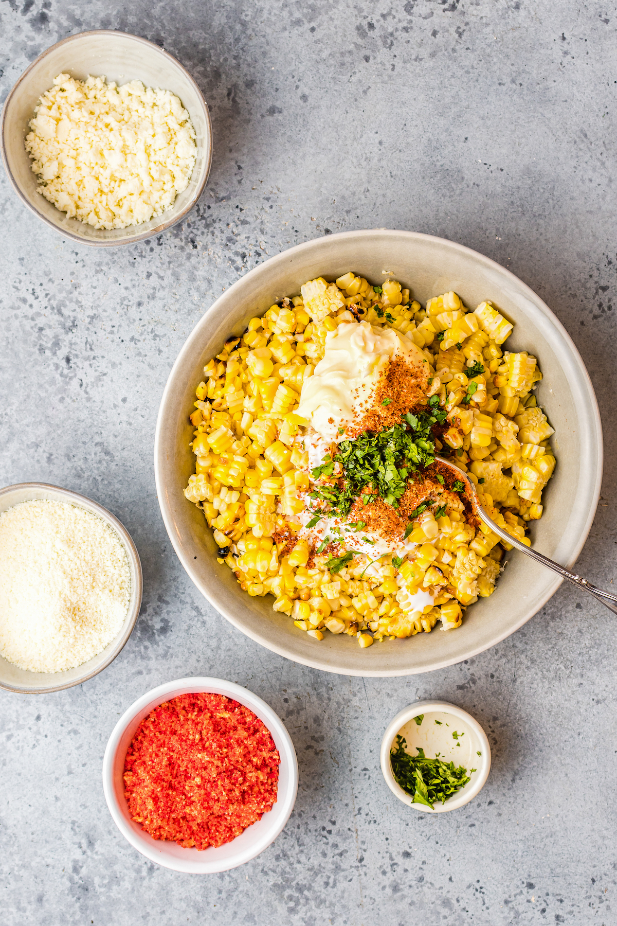 Corn, mayonnaise, tajin, and other ingredients in a bowl.