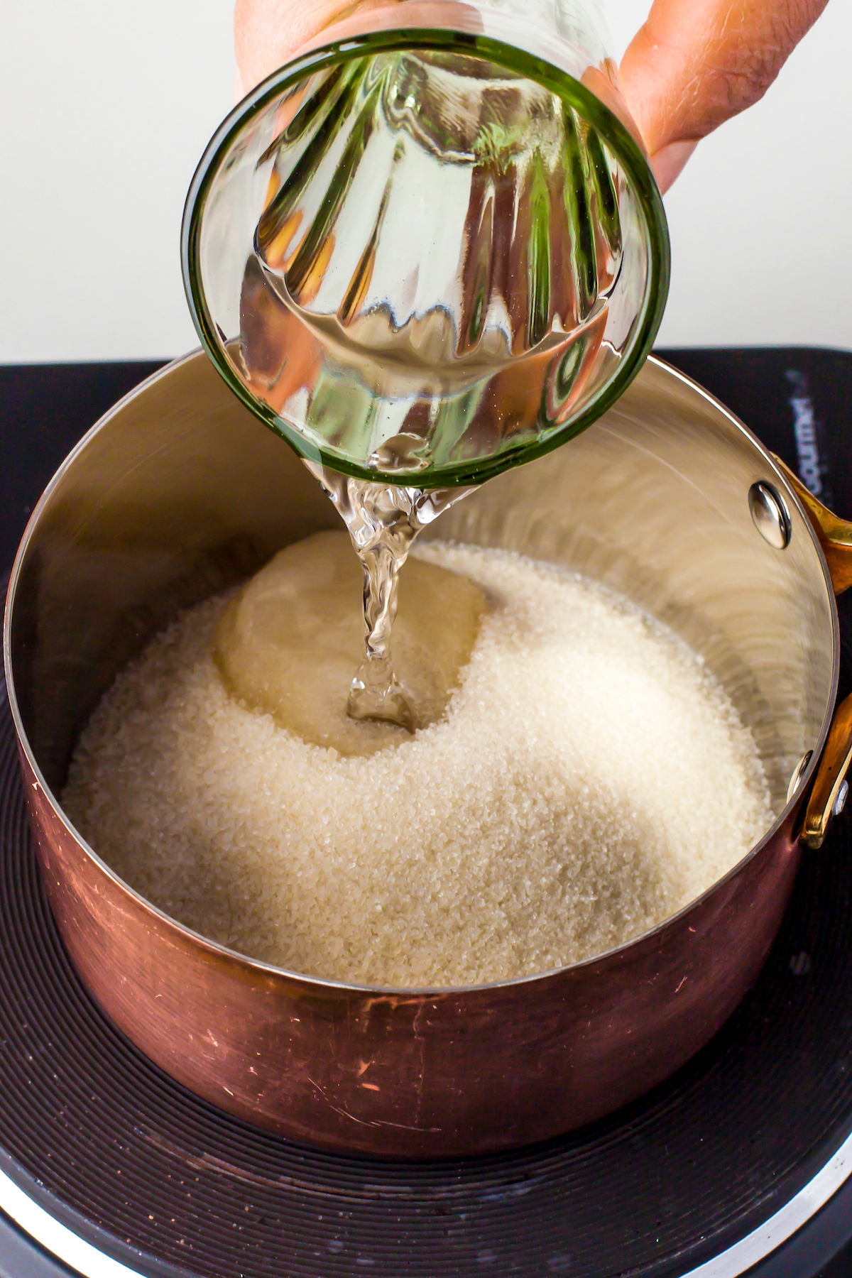 Pouring water into a pot with sugar to make simple syrup