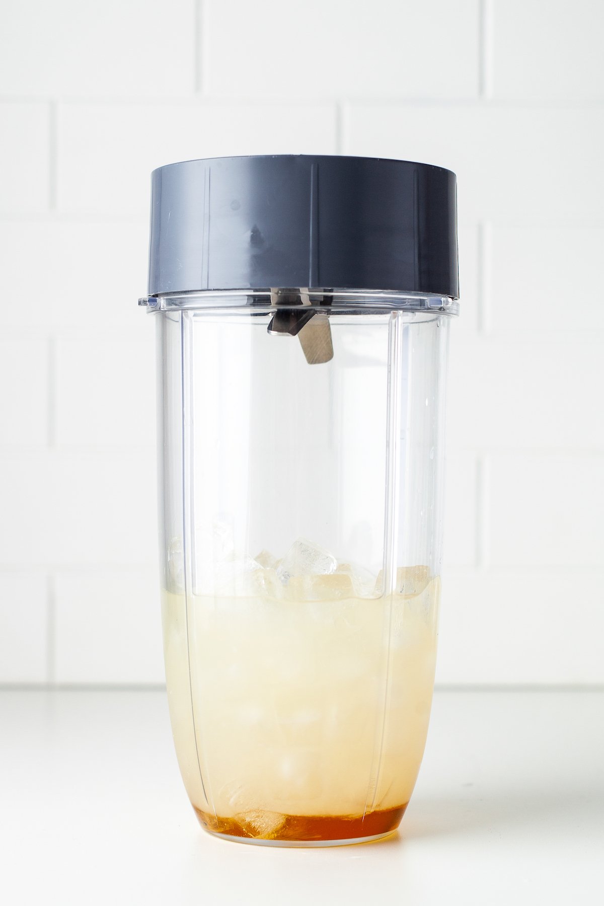 a blender cup with ingredients to make a frozen margarita like lime juice, liquor, and sweeteners