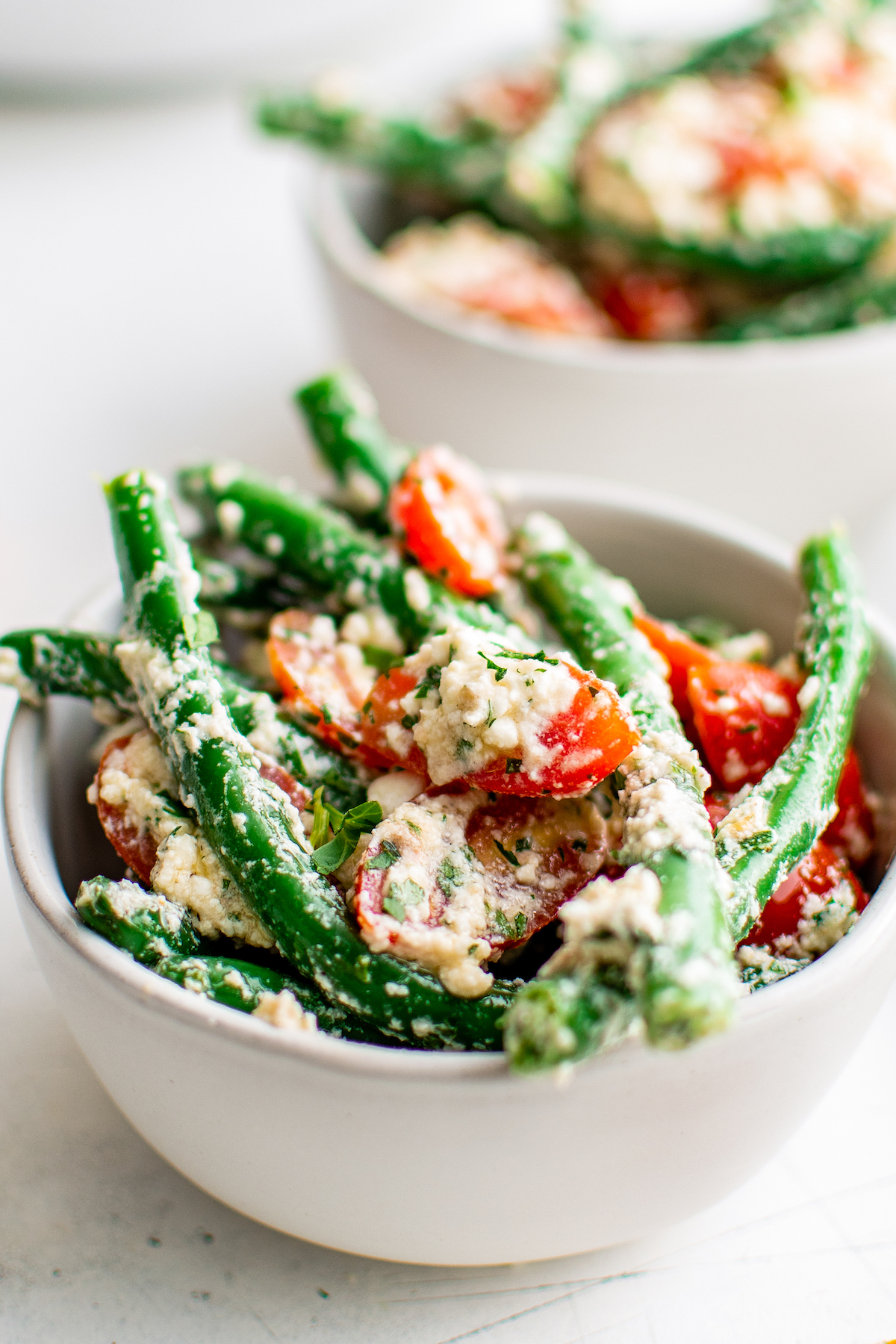 a bowl of green bean salad with grape tomatoes and feta