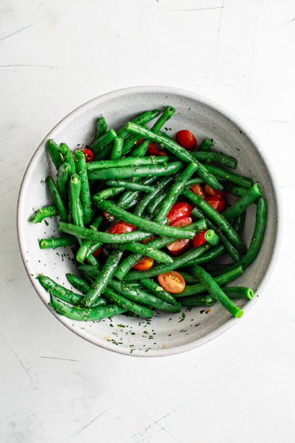 green beans in a bowl tossed with grape tomatoes and parsley