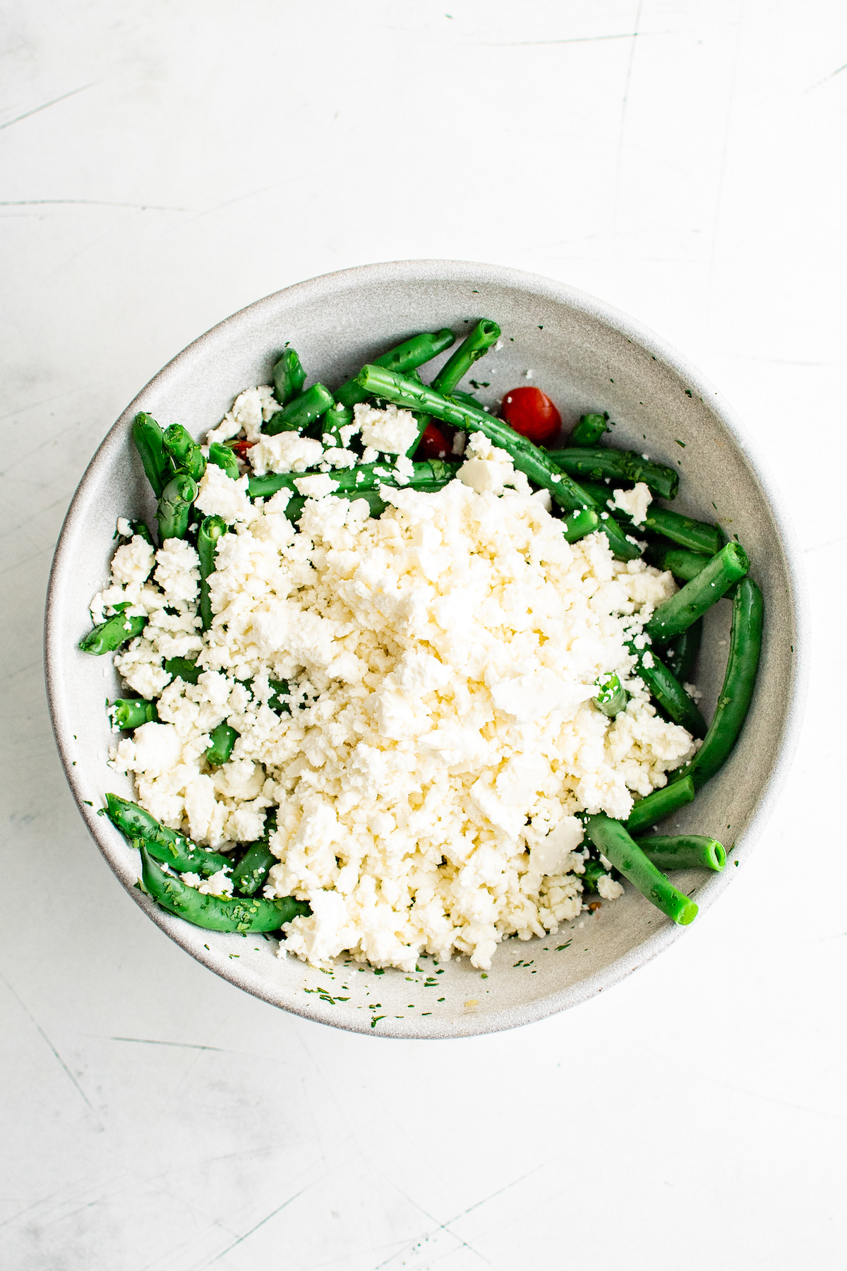 green beans in a bowl topped with a large scoop of feta cheese