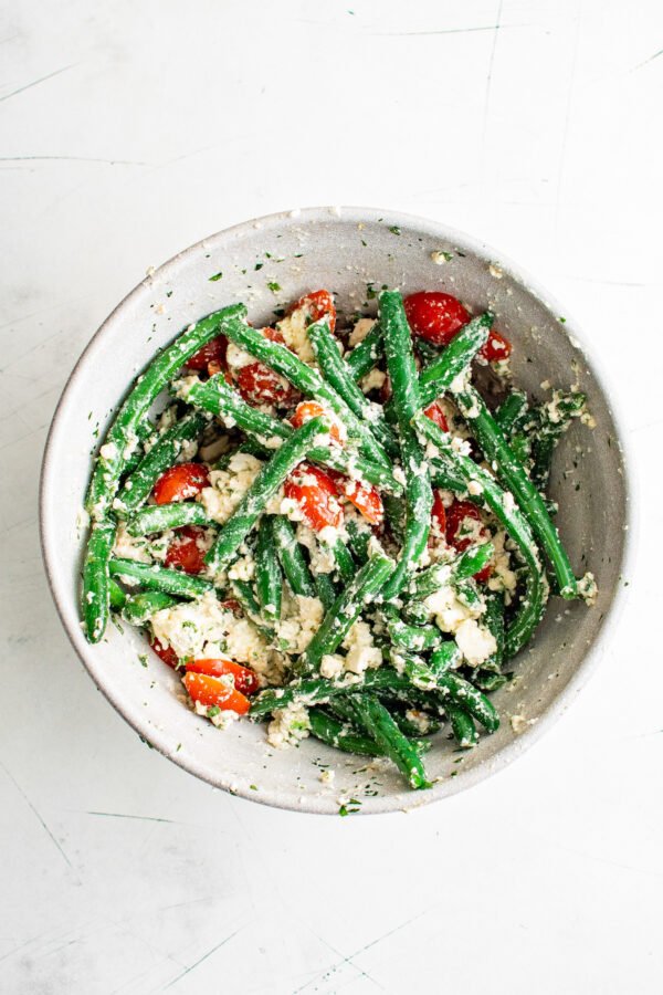 green beans in a bowl tossed with feta and grape tomatoes