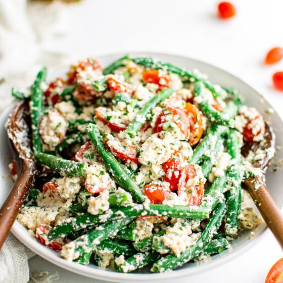 a large bowl of green bean salad with grape tomatoes and feta