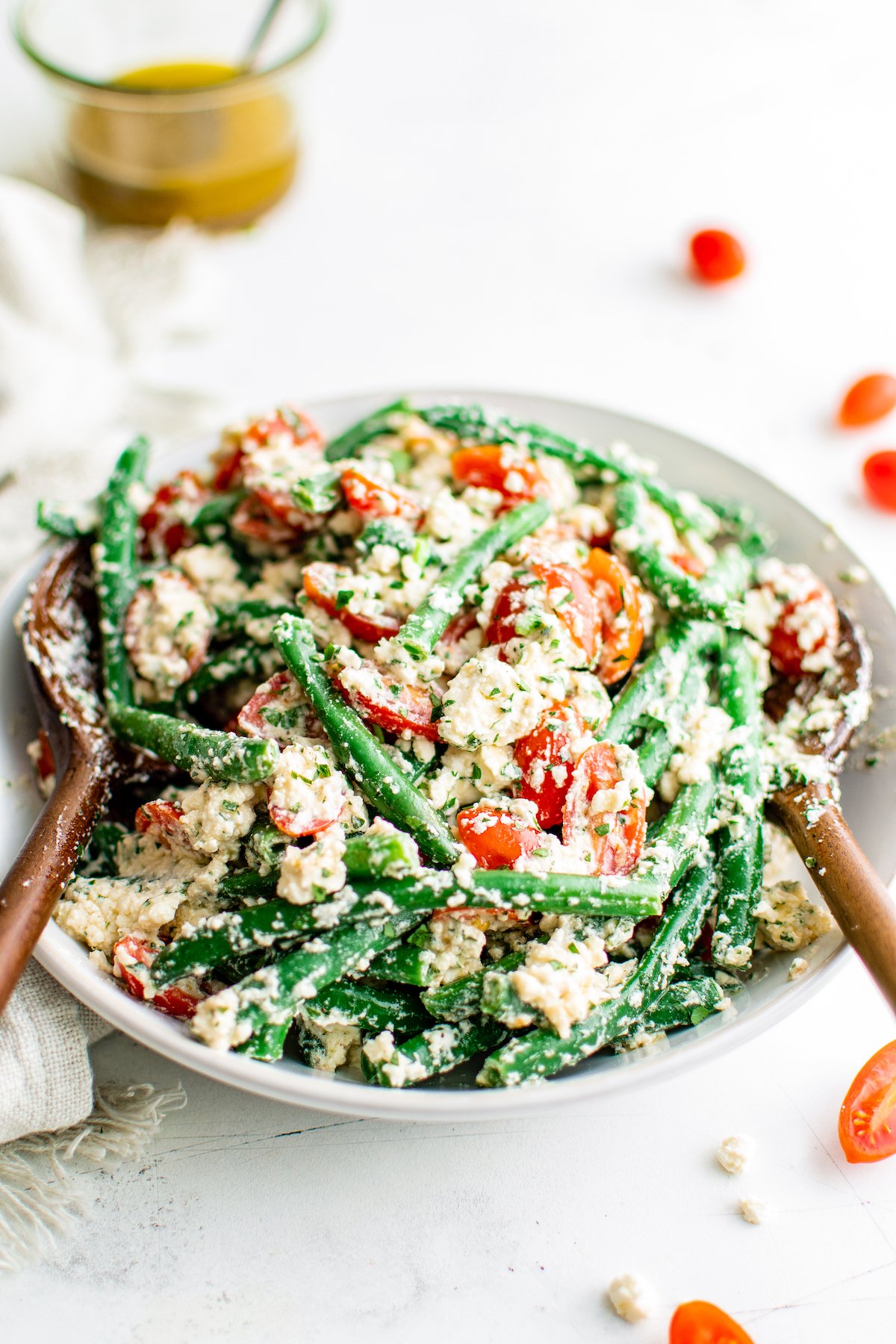 a large bowl of green bean salad with grape tomatoes and feta