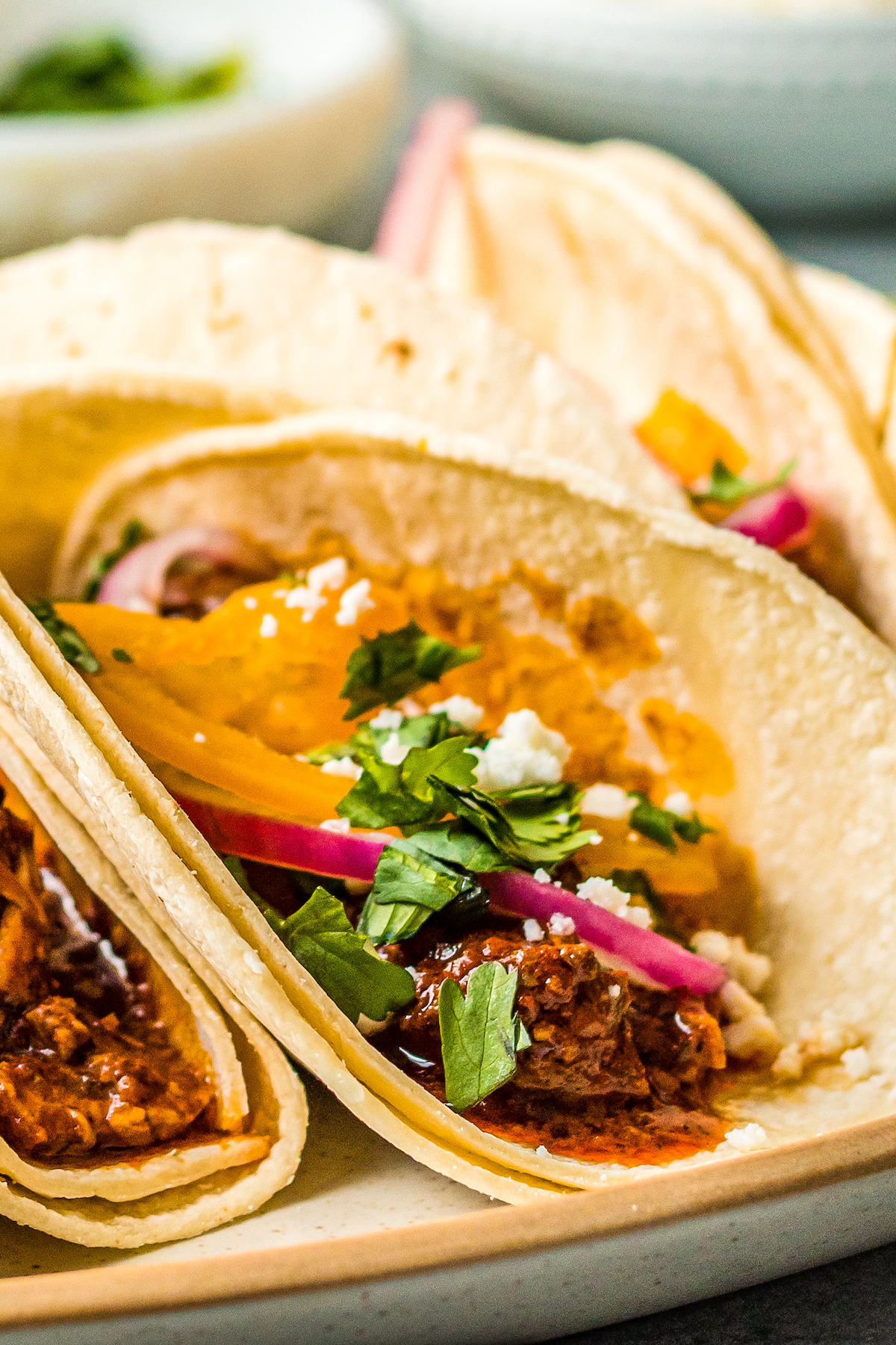 Corn tortilla tacos filled with pork, red onions, and herbs