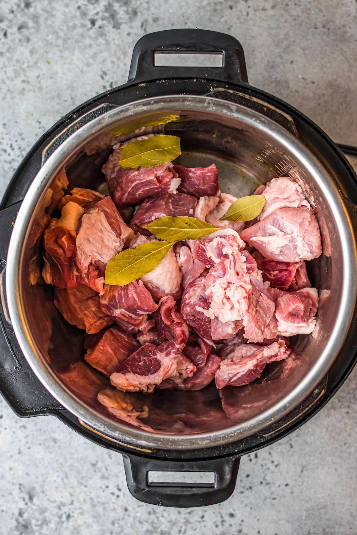 uncooked pork meat and bay leaves in an Instant Pot