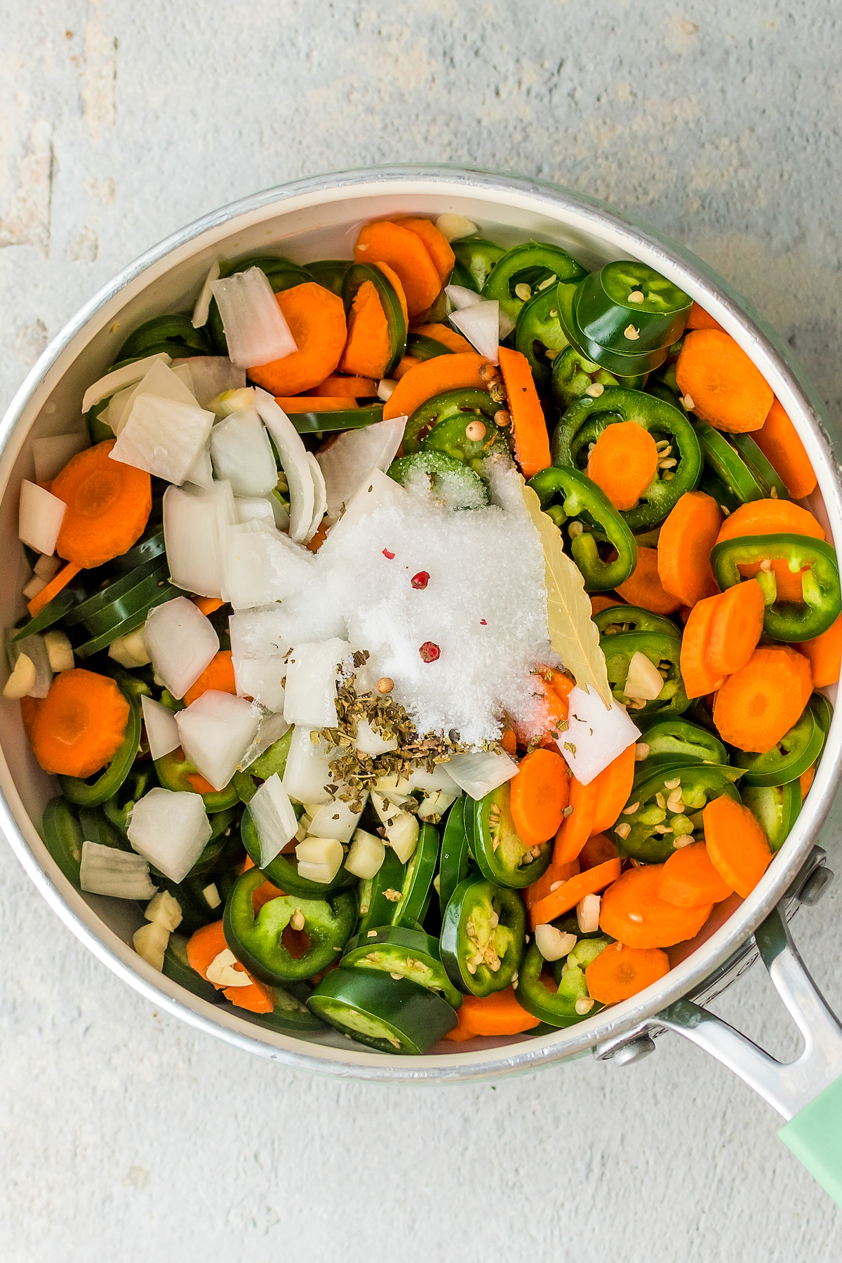 Carrots, onions, jalapenos, vinegar, and other pickling ingredients in a saucepan.