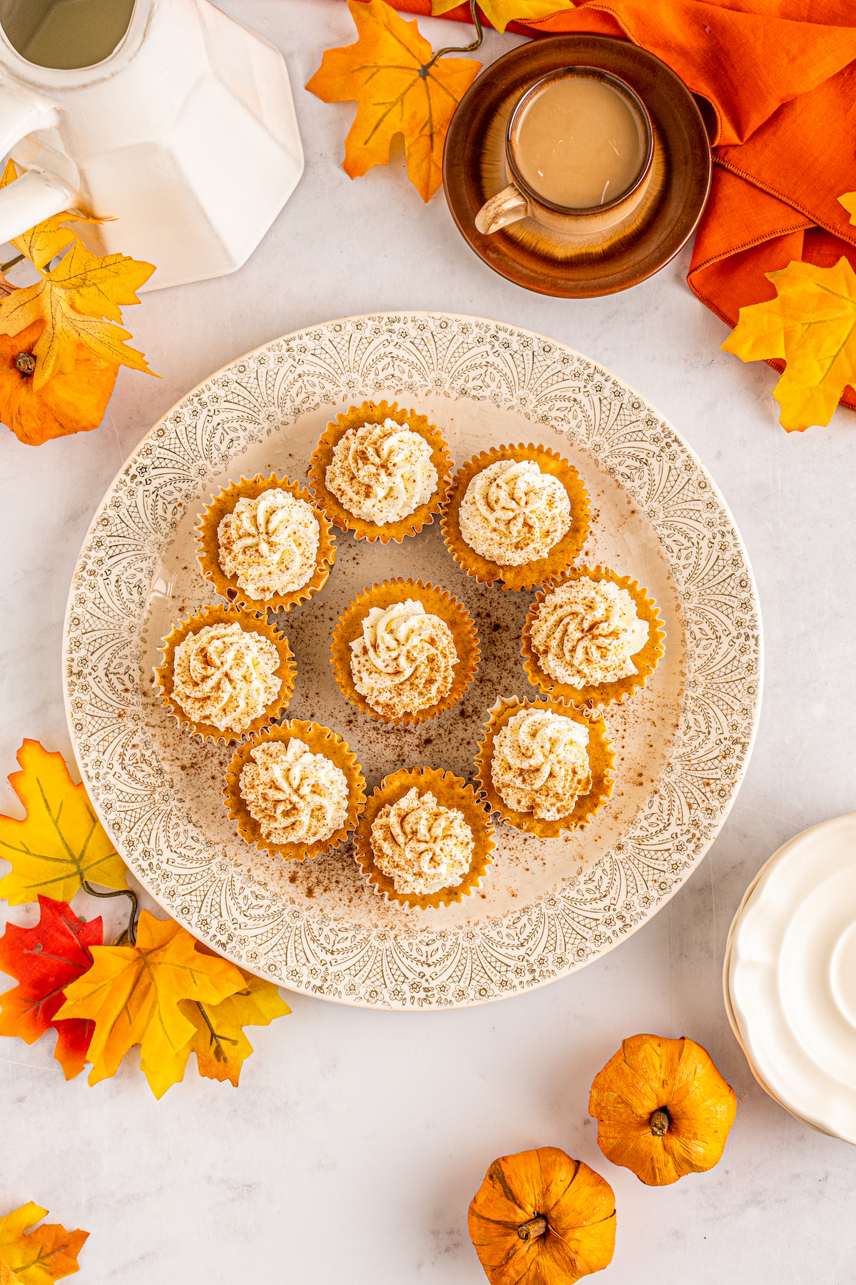 top view of a platter with mini pumpkin cheesecakes topped with whipped cream