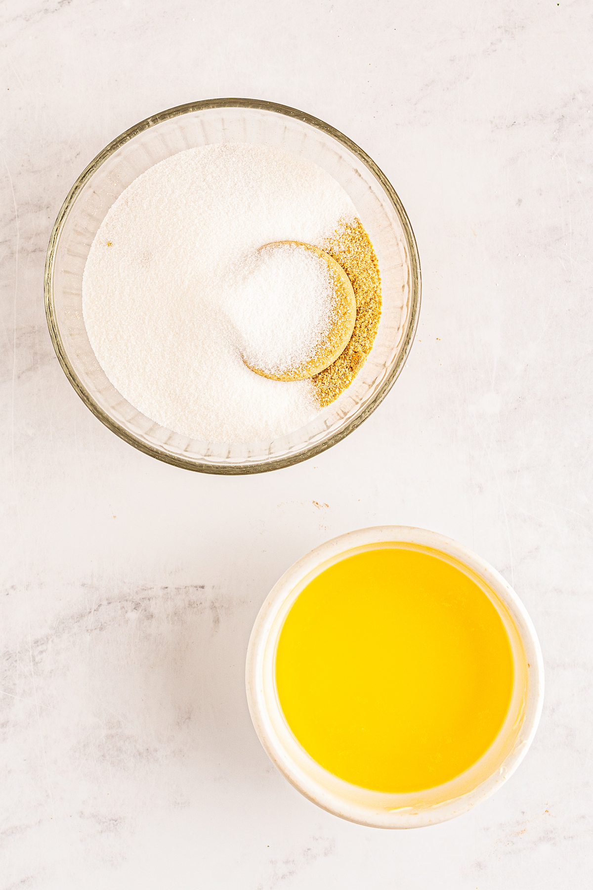 two bowls, one with melted butter and the other with sugar and graham cracker crumbs