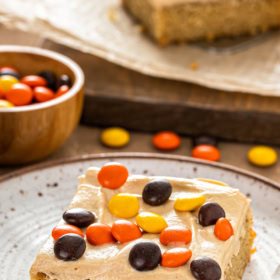 A slice of peanut butter cake with peanut butter frosting with candies on top.