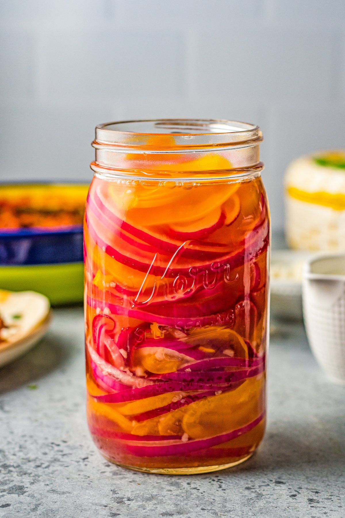 a mason jar of pickled red onions and habanero peppers