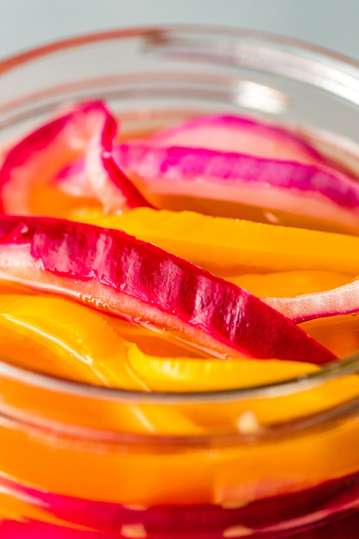 close up of pickled red onions and habanero peppers in mason jar