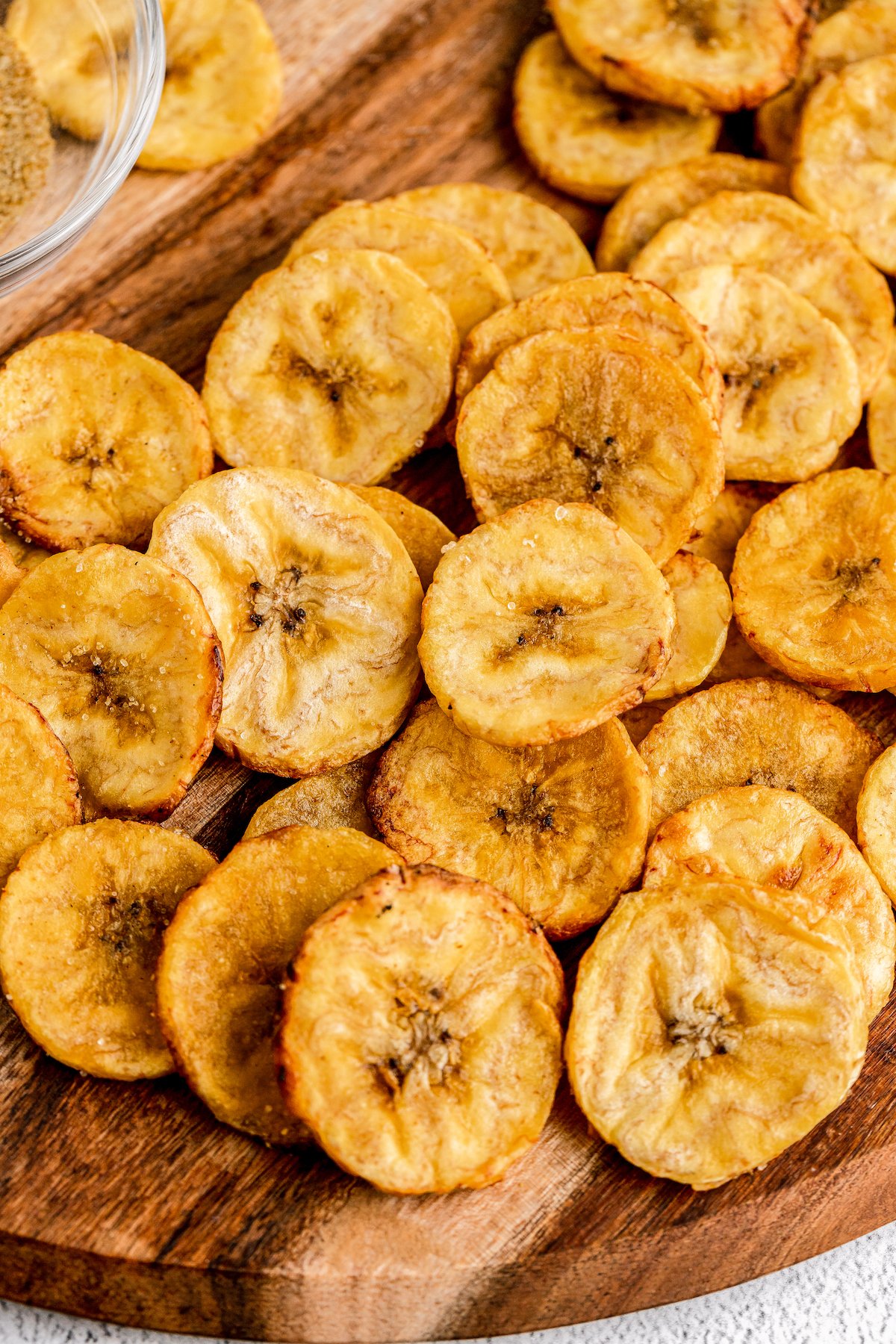 Golden-brown, baked plantain crisps on a cutting board.