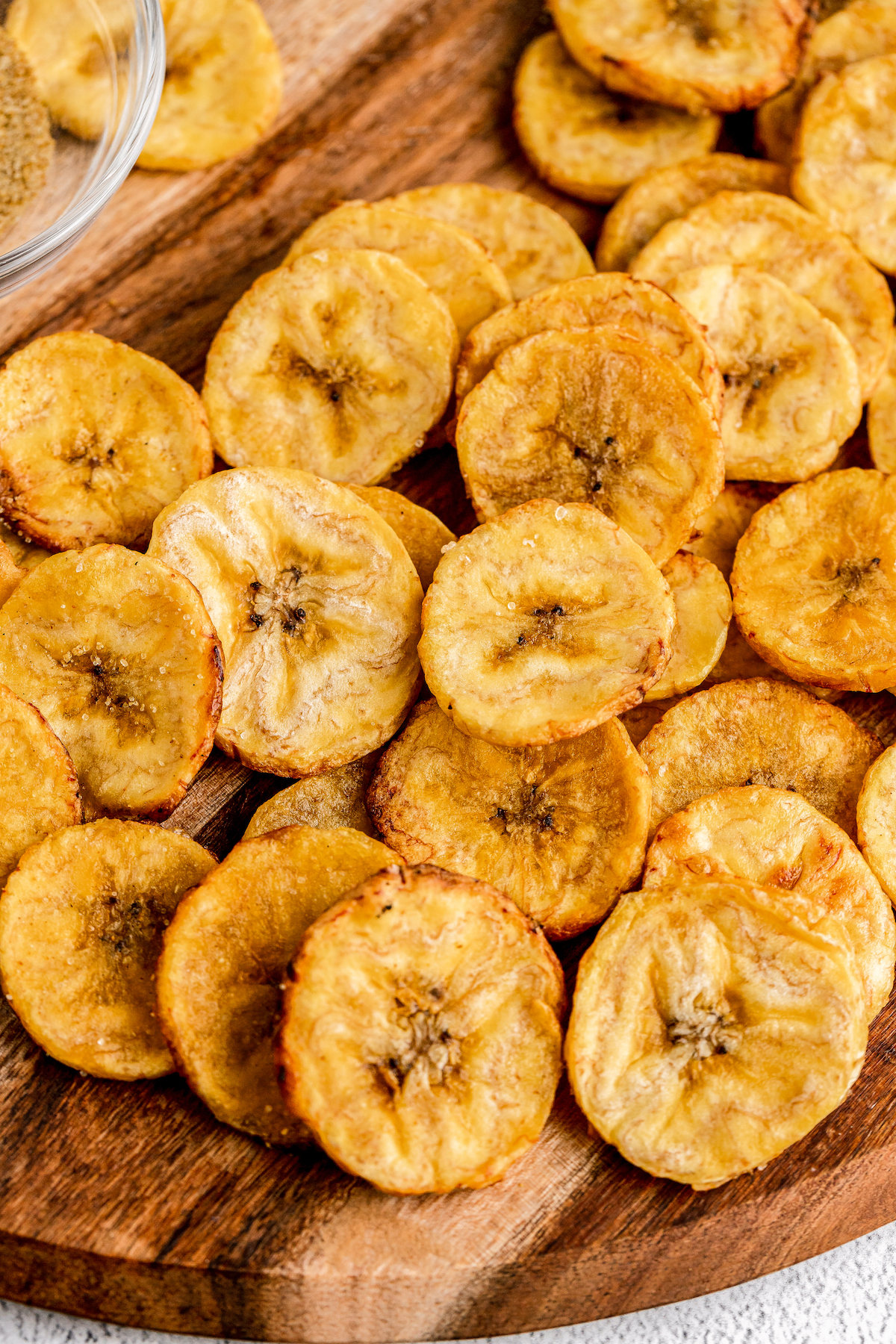 Golden-brown, baked plantain crisps on a cutting board.