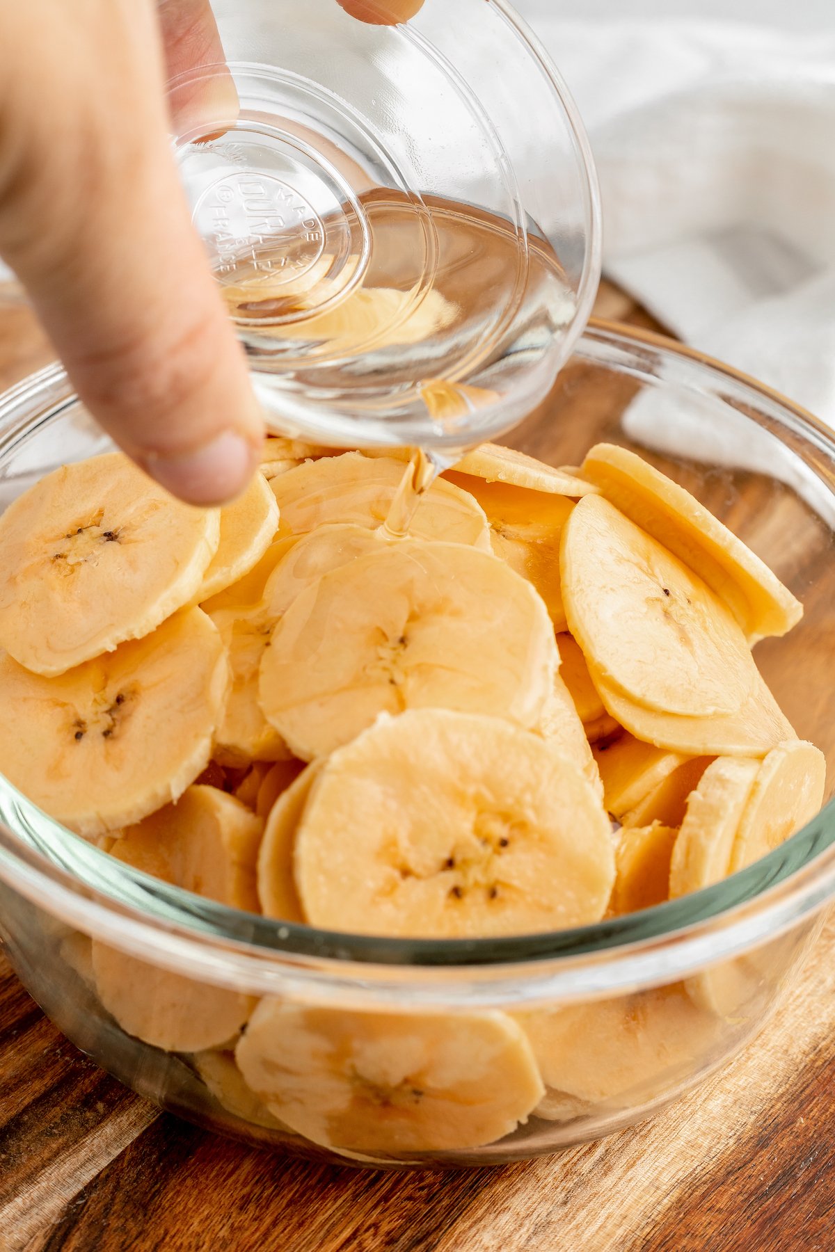 Plantain slices being drizzled with oil.