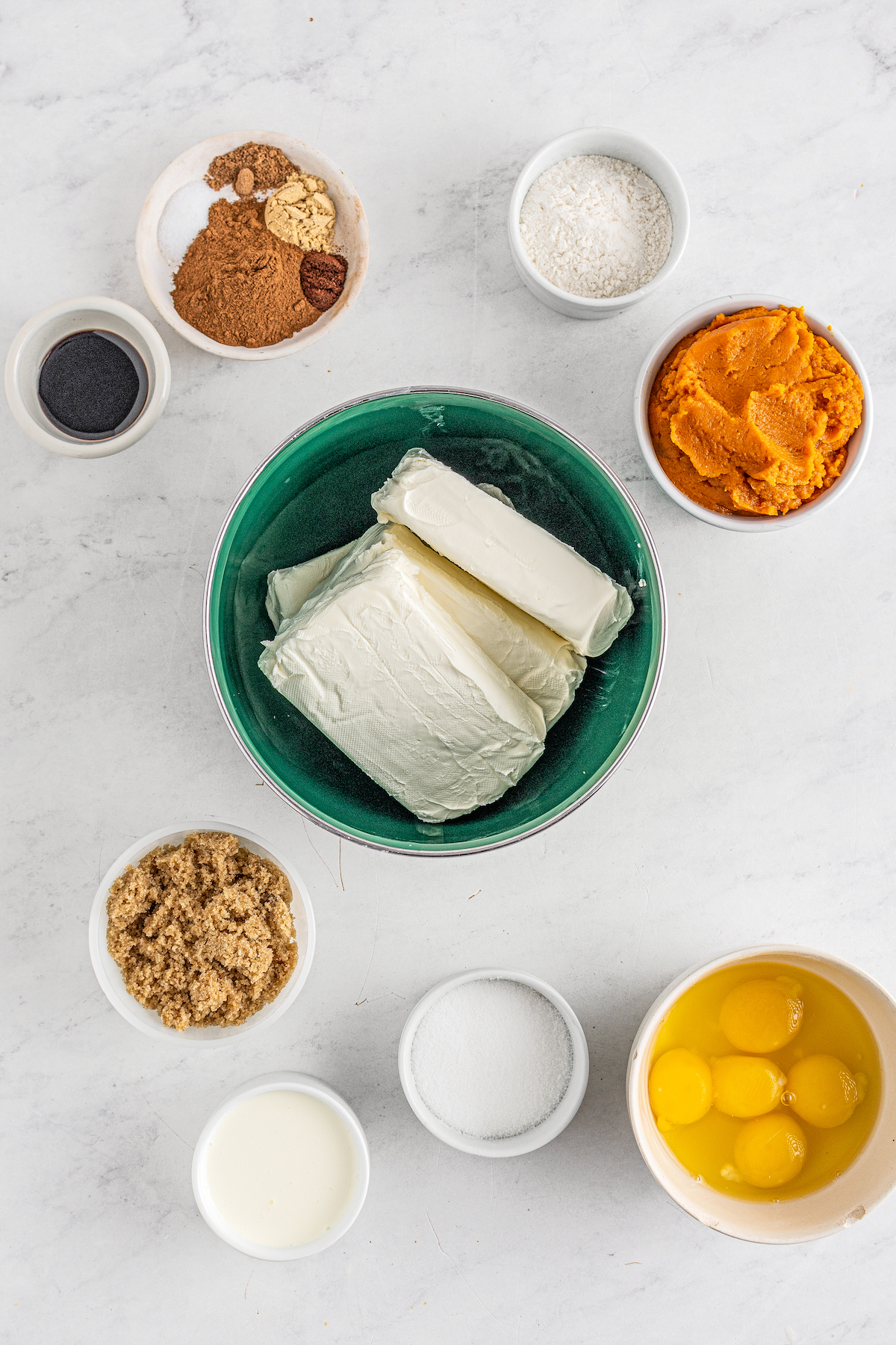 From top left: vanilla, spices, sugar, pumpkin puree, cream cheese, brown sugar, heavy cream, eggs and egg yolks, flour.