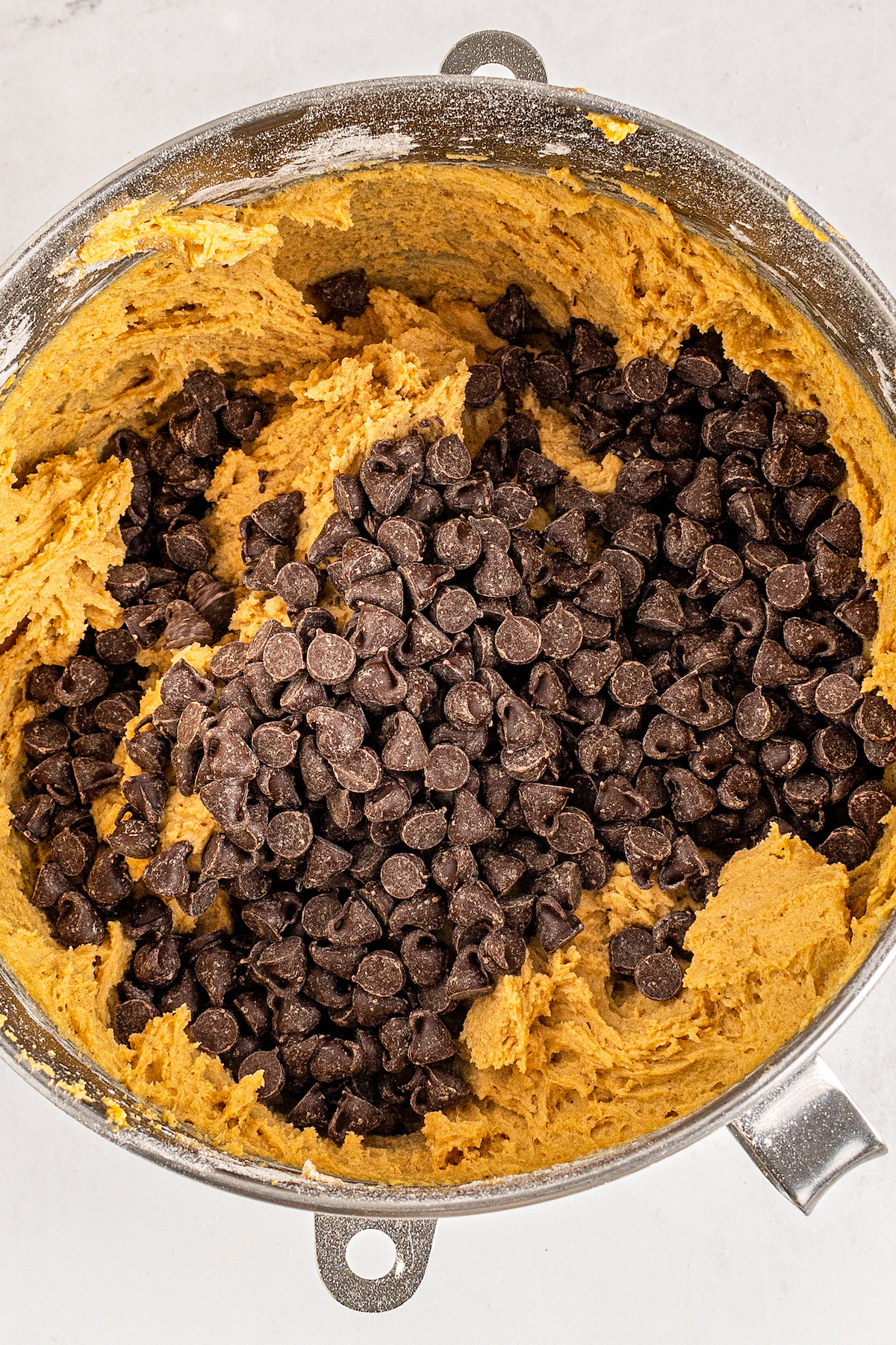 added chocolate chips to cookie dough in a large mixing bowl