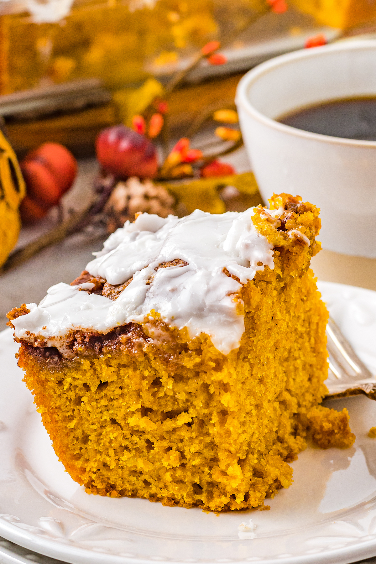Pumpkin cake with a sweet glaze, next to a cup of coffee.