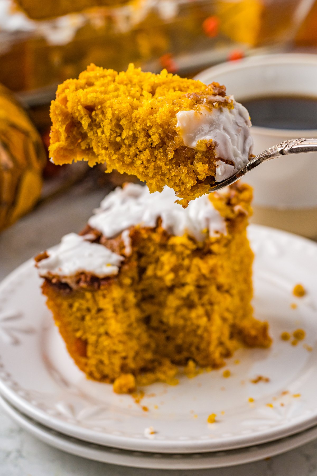A fork lifting a bite of pumpkin cinnamon roll cake toward the camera.