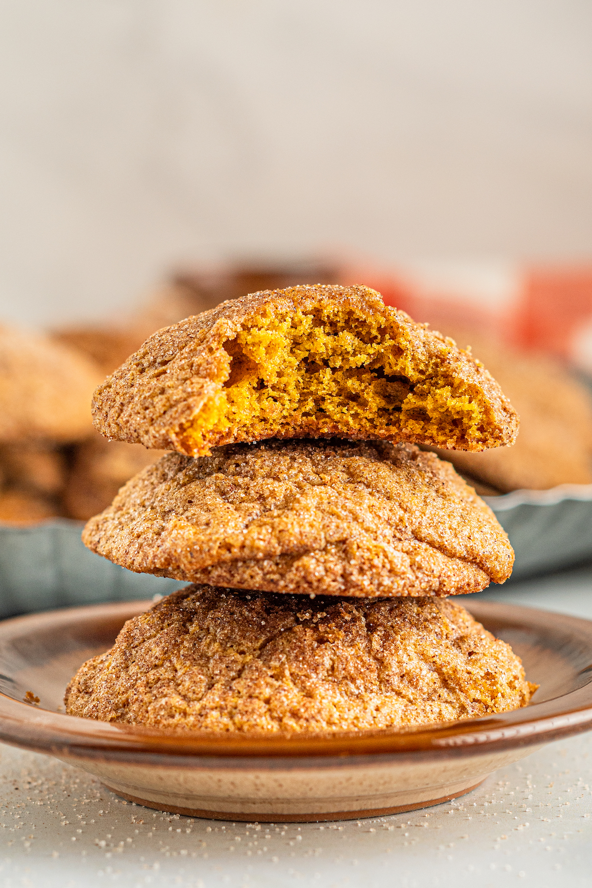 Three Pumpkin Cookies stacked on top of each other with a bite taken out of the topmost cookie in the stack.