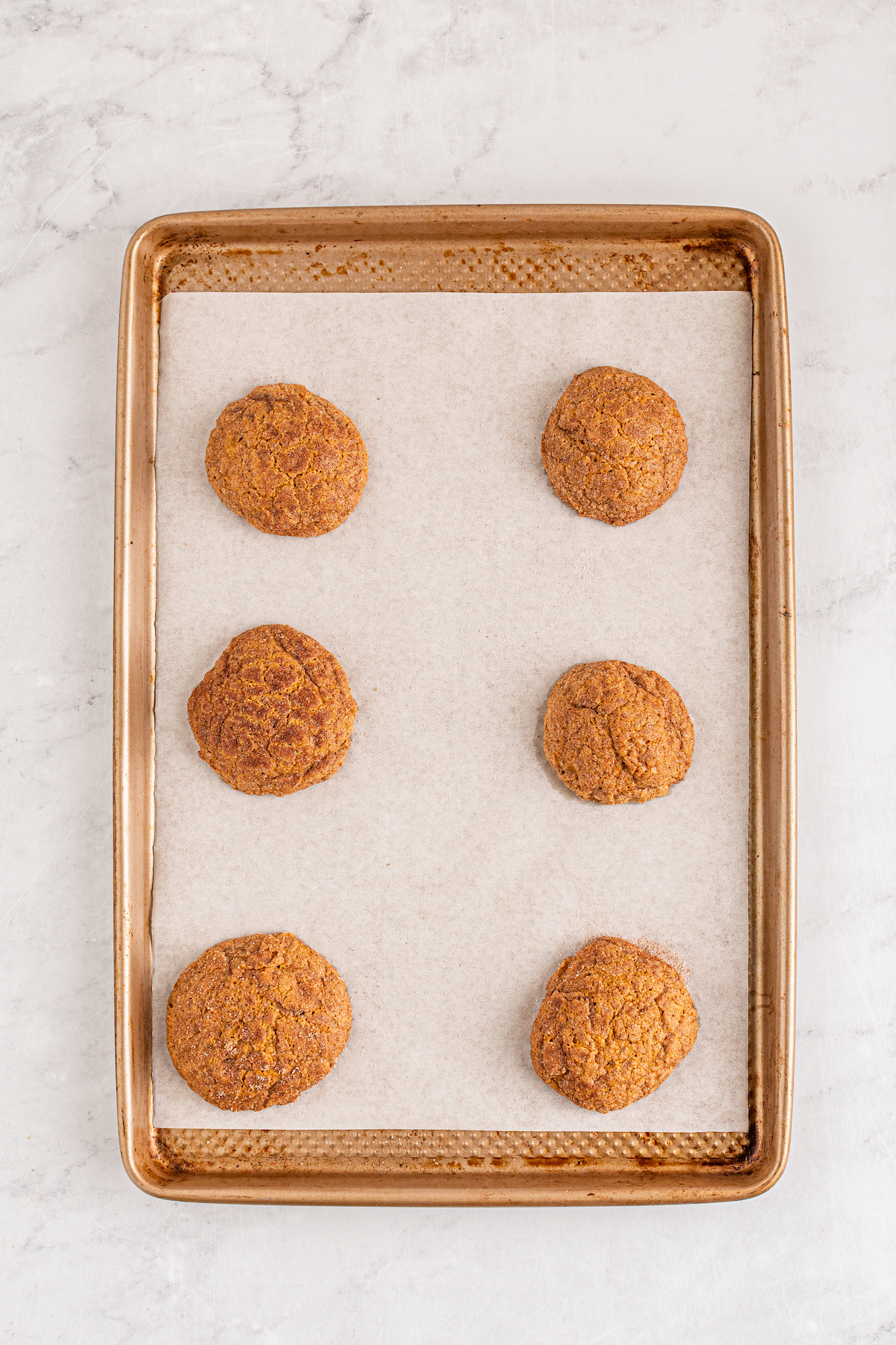 Pumpkin Cookies on a parchment lined baking sheet fresh out of the oven.