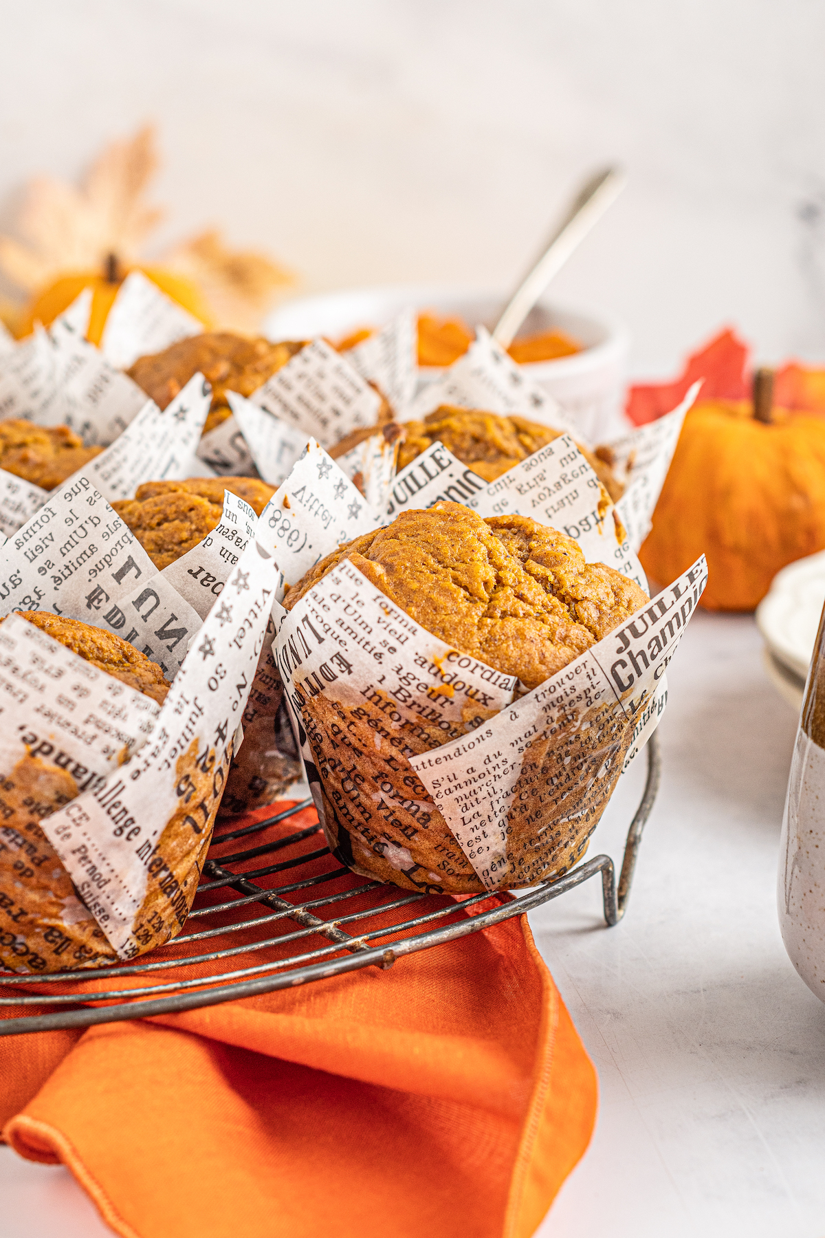 Close-up shot of pumpkin spice muffins in newsprint-style parchment liners.