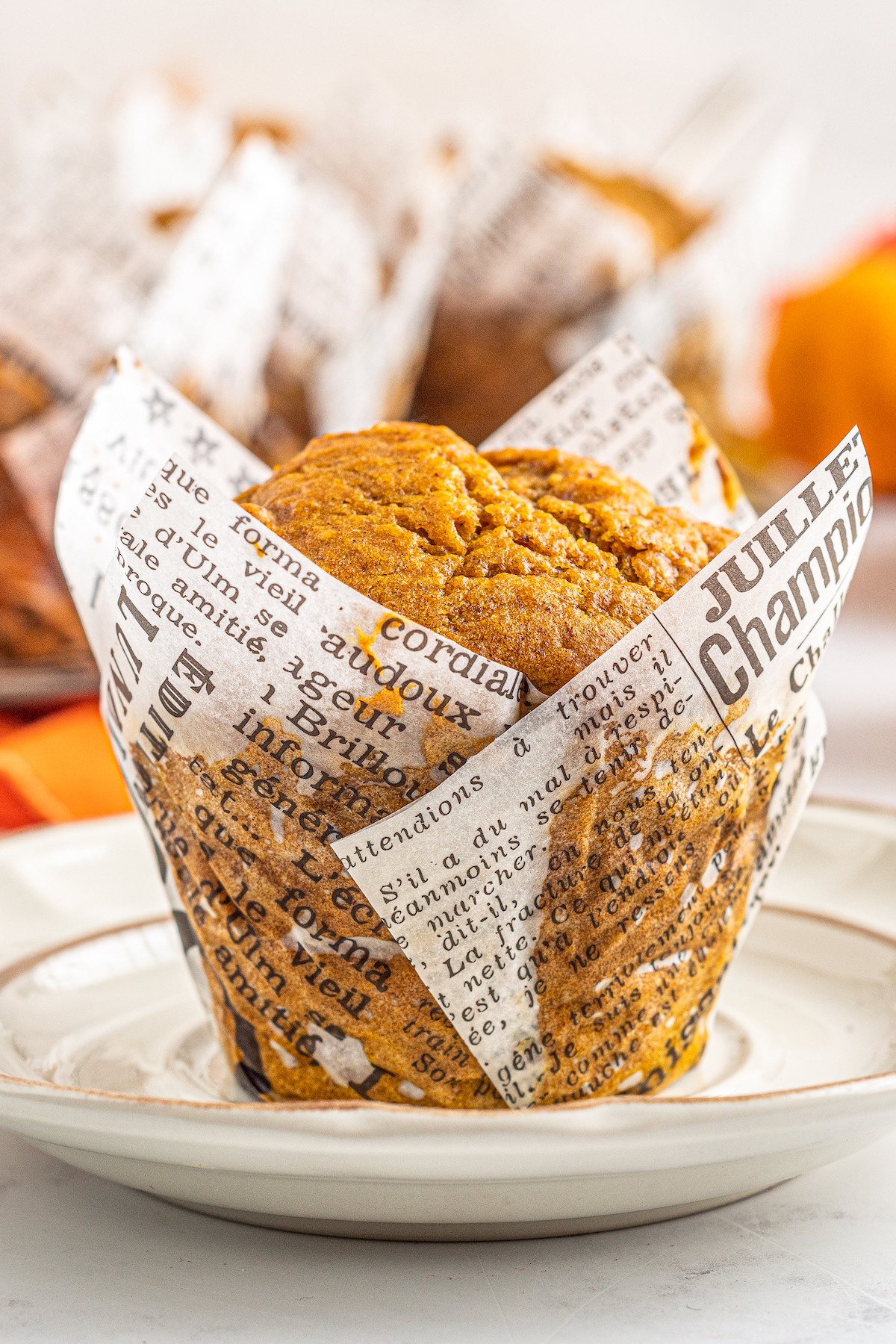A newspaper wrapper is wrapped around a single pumpkin muffin.