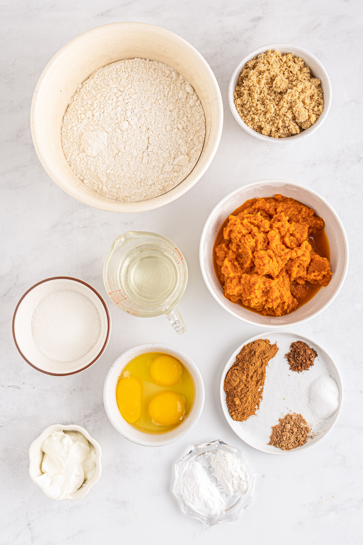 From top: All-purpose flour, brown sugar, white sugar, pumpkin, eggs and an extra egg yolk, spices and salt, sour cream, baking powder, baking soda.