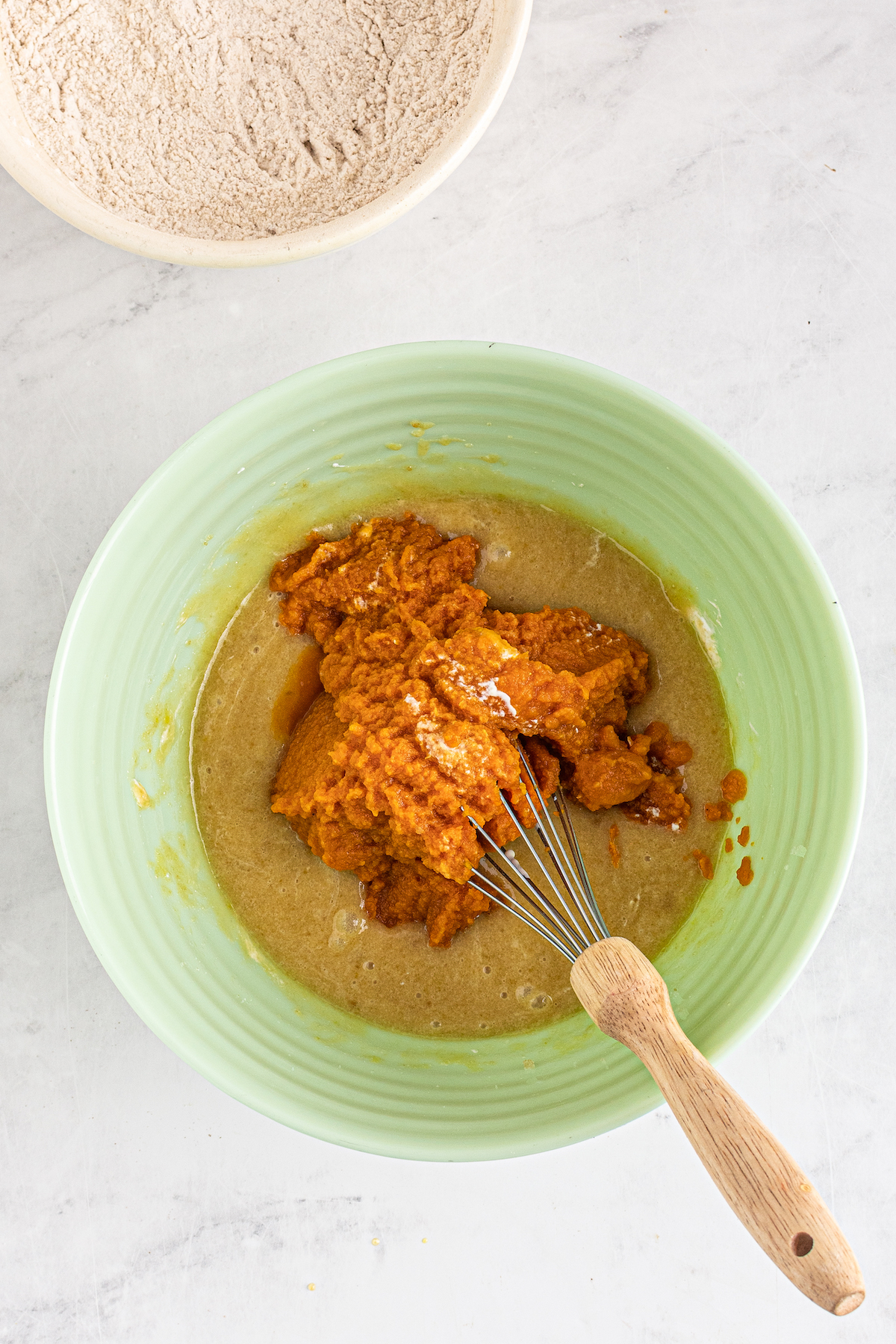 Pumpkin puree being stirred into muffin batter.