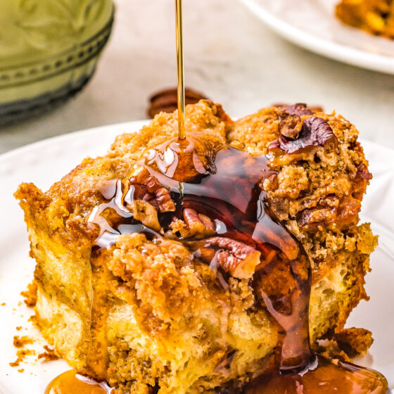 A single serving of Pumpkin Pecan French Toast Casserole with maple syrup being poured over the top of it.