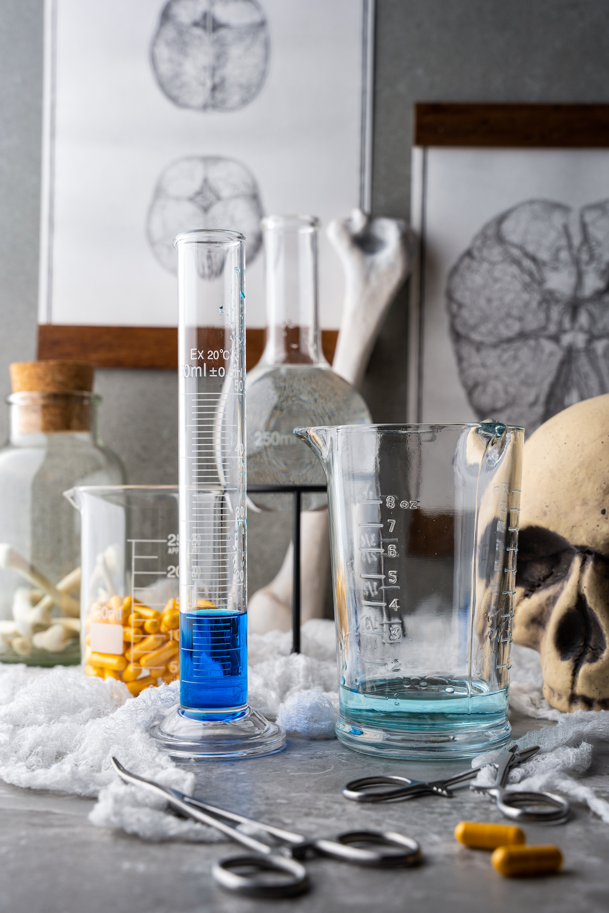 a tall graduated cylinder with blue curacao on a tablescape with other mad scientist themed Halloween decorations
