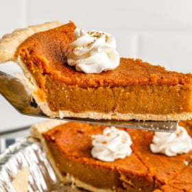 A sweet potato buttermilk pie being lifted out of a baking pan.