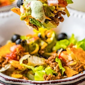 A chopped up salad in a bowl with a fork taking a bite.